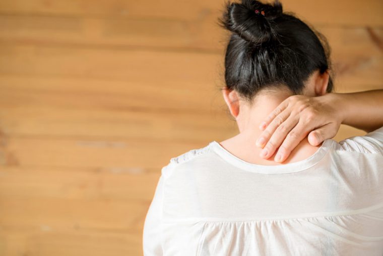 A patient touching the back of her neck